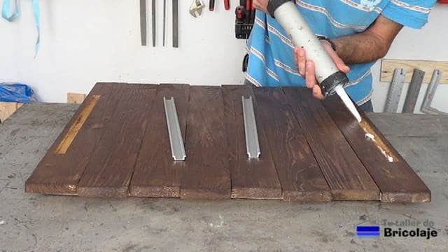 aplicando un adhesivo de montaje para pegar los perfiles para las tiras de leds a la madera de palets