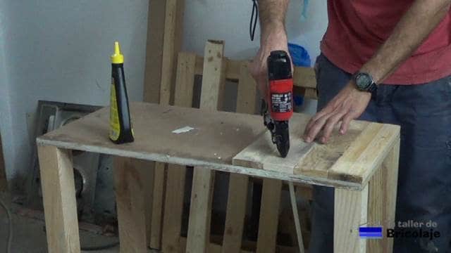 pegando y clavando con tachas o clavos la cubierta superior de madera de palets