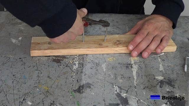 usando unos alicates para colocar las alcayatas en la madera de palets para colgar las brochas y rodillos