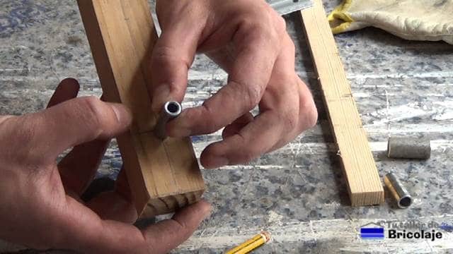 presentando el casquillo metálico sobre la madera para fabricar la guía para unir madera mediante espigas o tarugos
