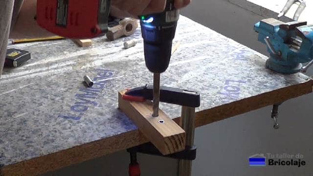 perforando con el taladro la madera para insertar el casquillo para abrir agujeros para insertar tarugos o espigas de 8