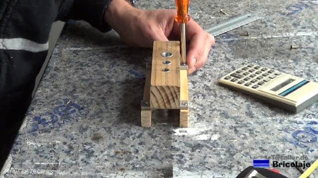 atornillando las pletinas a los listones laterales de la guía para unir madera mediante tarugos o espigas