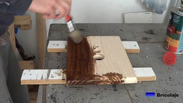 aplicando tinte a la madera que formará el aplique de pared