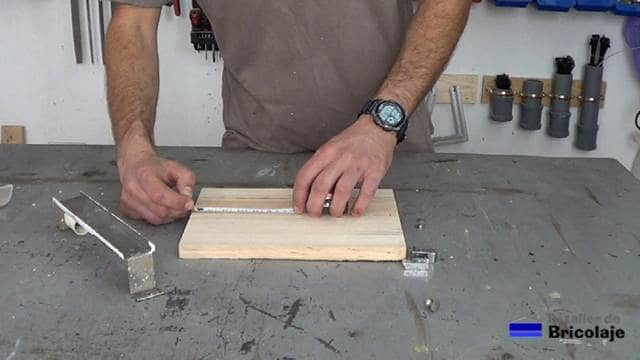 marcando el lugar donde hacer los agujeros en la madera para sujetarla al soporte de pared