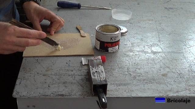 preparando la masilla de fibra de vidrio para tapar o rellenar el agujero en el hierro o metal
