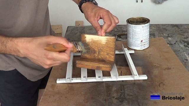 aplicando el barniz tinte al soporte de madera para tableta o tablet